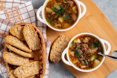 İki tabak mercimek çorbası ve ahşap bir tahtanın üstünde tavuk, üst manzara.