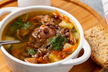 Tahtadaki beyaz kasede tavuklu mercimek çorbası.