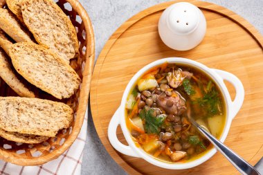 Tahta bir tahtanın üstünde tavuklu mercimek çorbası.