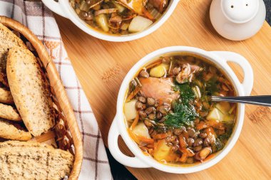 Siyah masa üzerinde ahşap bir tahta üzerinde mercimek çorbası ve tavuk ile iki tabak, üst görünümü