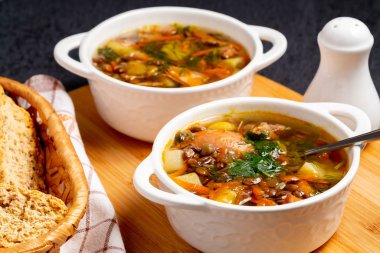 İki tabak mercimek çorbası ve siyah masadaki tahta tahtada tavuk.