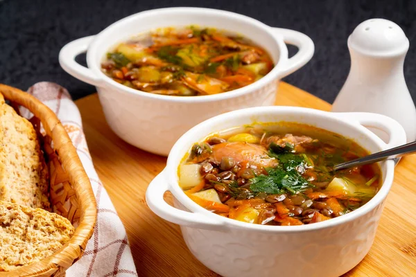 İki tabak mercimek çorbası ve siyah masadaki tahta tahtada tavuk.