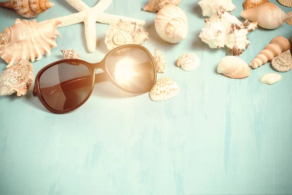 Fundo azul do mar com óculos de sol e conchas, férias de verão e conceito de tempo de férias — Fotografia de Stock