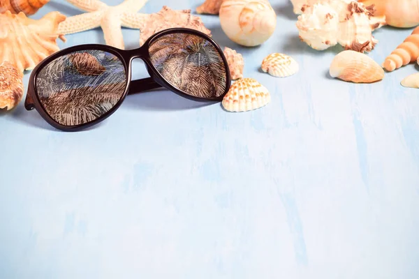 Fundo azul do mar com óculos de sol e conchas, férias de verão e conceito de tempo de férias — Fotografia de Stock