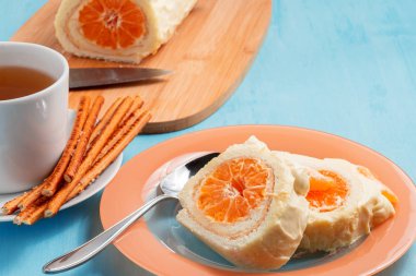 Krem şanti ve mandalina dolgu ve bir fincan çay ile Tatlı rulo