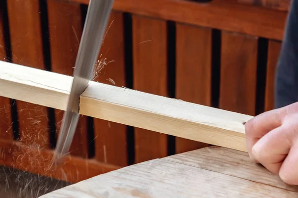 Чоловічі руки розпилюють дерев'яну планку з ножівкою — стокове фото