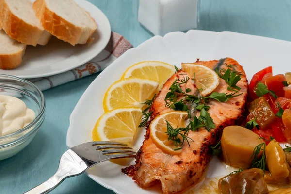 Baked salmon fillet medallion with salad of pickled vegetables and mushrooms on a white plate on a blue background — Stock Photo, Image