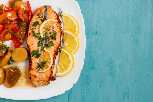 Baked salmon fillet medallion with salad of pickled vegetables and mushrooms on a white plate on a blue background, top view, flatlay, place for text, copy space — Stock Photo, Image