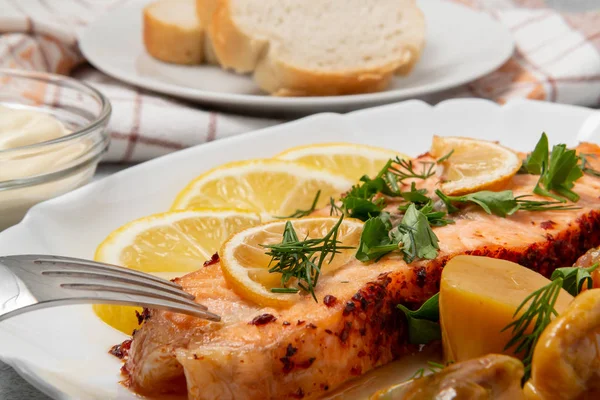 Baked salmon fillet medallion with salad of pickled vegetables and mushrooms on a white plate on a gray background, close up — Stock Photo, Image