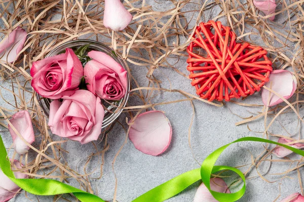 Rosas rosadas y un corazón de mimbre con decoraciones en la mesa un concepto de amor y felicitaciones por un ser querido — Foto de Stock