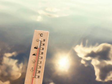 Bulutların ve güneşin yansıması ile göl suyunun arka planında 30 derece ısı gösteren termometre