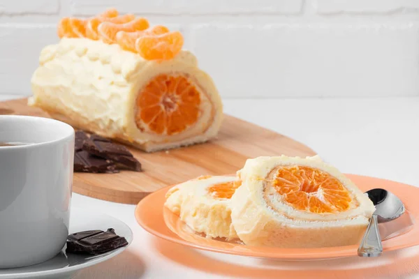 Rouleau sucré avec crème fouettée et garniture à la mandarine et une tasse de thé — Photo