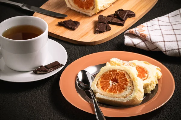Солодкий рулет зі збитими вершками та мандариновою начинкою та чашкою чаю — стокове фото