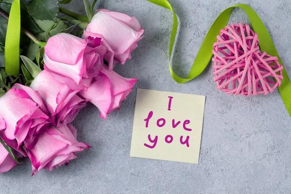 Ramo de rosas rosadas, un corazón y una nota con la inscripción Te amo en la mesa el concepto de amor y cuidado — Foto de Stock