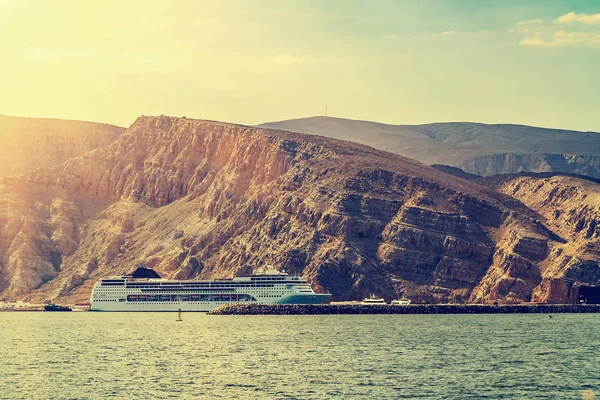 Touristenschiff an der Küste hinter Felsen in den Fjorden des Golfs von Oman — Stockfoto