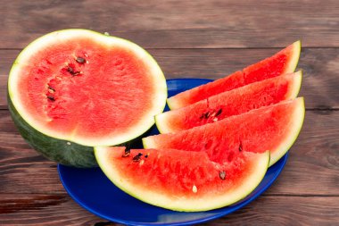 Tahta bir masada mavi bir tabakta dilimlenmiş kırmızı karpuz.