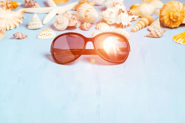 Fundo azul do mar com óculos de sol e conchas, férias de verão e conceito de tempo de férias — Fotografia de Stock