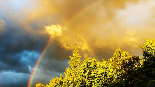 Regnbåge efter regn i en molnig himmel bland dramatiska moln — Stockfoto