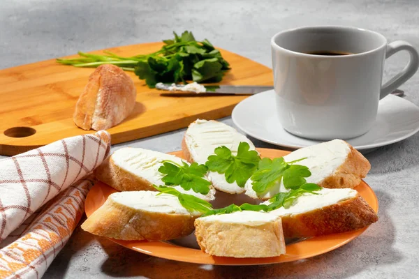 Свіжі бутерброди з вершковим сиром та петрушкою на тарілці, рубання дерев'яної дошки та чашка кави концепція ранкового сніданку — стокове фото