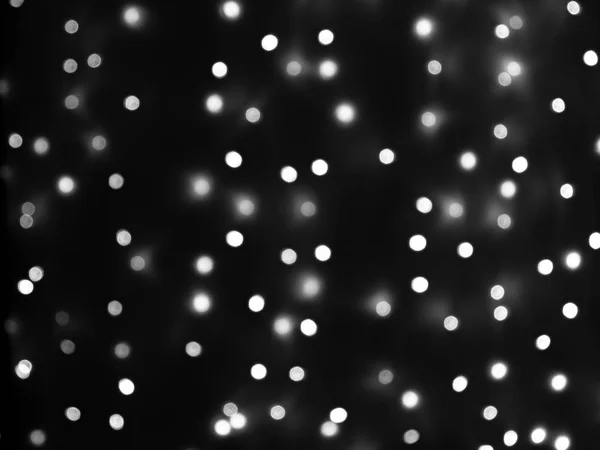 Defocused lights of Christmas garland in black and white evenly distributed over the area of the frame, background, texture — Stock Photo, Image