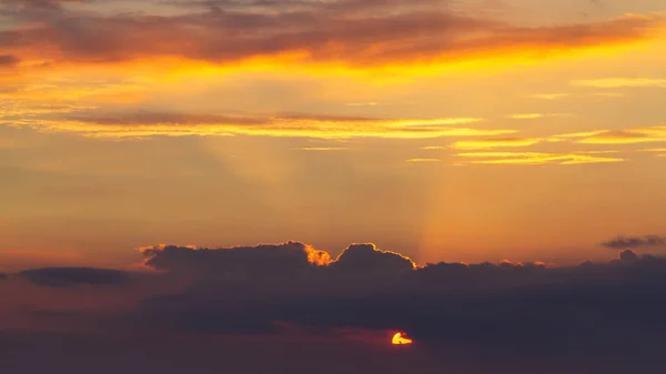 Himmel under en färgglad, ljus orange solnedgång, Solar strålar göra sig igenom molnen — Stockfoto