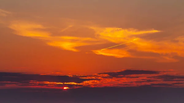 Himmel under en färgglad, ljus orange solnedgång, Solar strålar göra sig igenom molnen — Stockfoto
