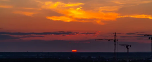 Verschillende bouw kranen op de achtergrond van kleurrijke zonsondergang hemel — Stockfoto