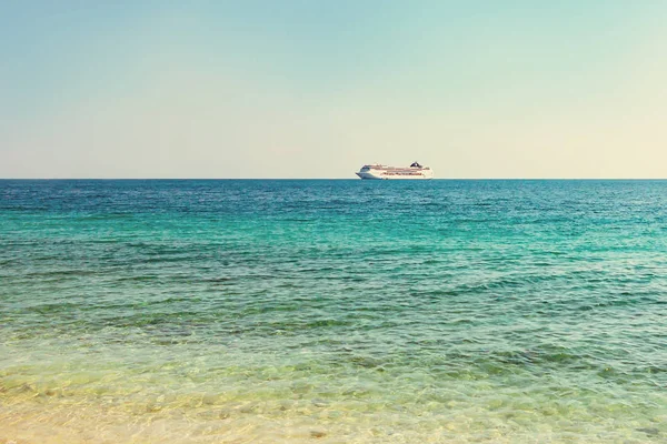 Mer turquoise avec de légères ondulations sur l'eau et un grand paquebot de croisière à l'horizon — Photo