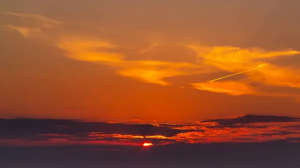 Himmel under en färgglad, ljus orange solnedgång, Solar strålar göra sig igenom molnen — Stockfoto