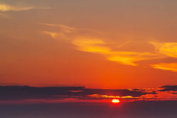 Himmel under en färgglad, ljus orange solnedgång, Solar strålar göra sig igenom molnen — Stockfoto