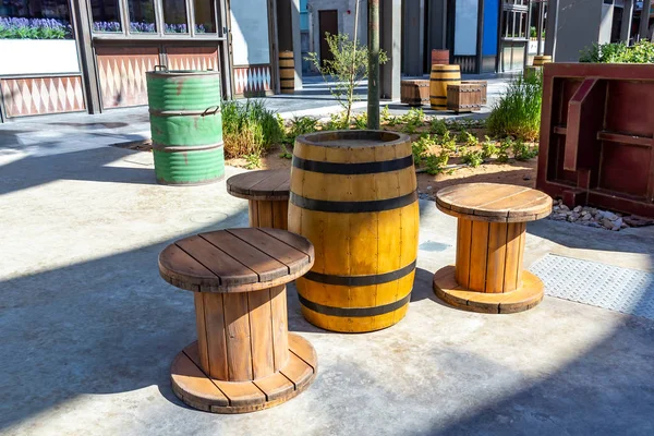 Unusual public space in the city - a table of old barrels and chairs of large coils for ropes