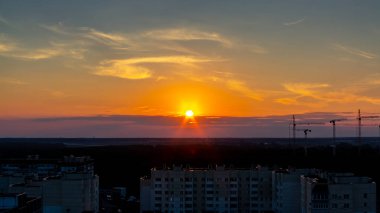 Renkli günbatımı gökyüzünün arka planında çeşitli inşaat vinçleri