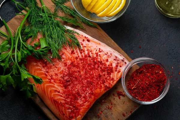 Piece of salmon fillet on a wooden cutting board with ingredients for its further preparation, top view - photo, image — Stock Photo, Image