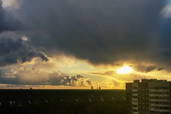 都市の郊外の雷雲を突き抜ける太陽の光 — ストック写真
