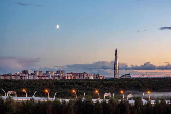 Paisaje urbano nocturno. Vista de la torre del Centro Lakhta en San Petersburgo al atardecer con nubes y luna — Foto de Stock