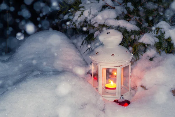 Lámpás egy égő gyertyát egy hóval borított karácsonyfa az udvarban, a ház a snowdrifts — Stock Fotó