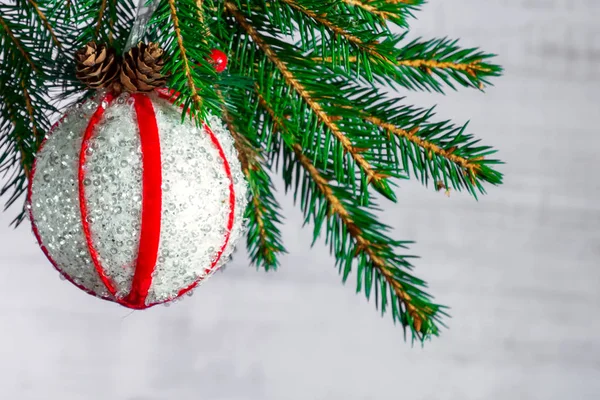 Ramo de uma árvore de Natal decorada com uma bola branca com fitas vermelhas e cones em um fundo de madeira. Espaço de cópia para texto — Fotografia de Stock