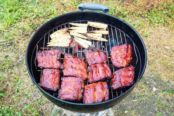 Gegrillte Schweinerippchen und Mini-Mais auf rundem Grill — Stockfoto