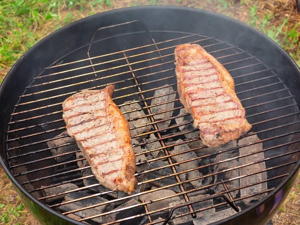 Dwie soczyste steki wołowe są grillowane na okrągłym grillu — Zdjęcie stockowe