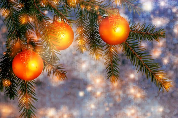 在闪闪发光的蓝银背景上的云杉枝上的橙色圣诞装饰品。新年或圣诞节背景 — 图库照片