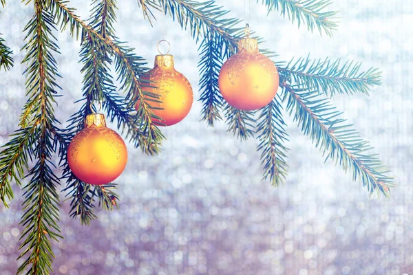 橙色的圣诞装饰品在云杉树枝上，在闪亮的银色背景。新年或圣诞节背景 — 图库照片
