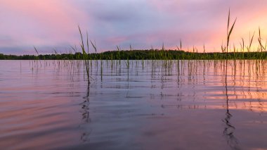 Gün batımında göl bulutlarının pürüzsüz suyuna yansır. Renkli manzara, arka plan bulanıklığı