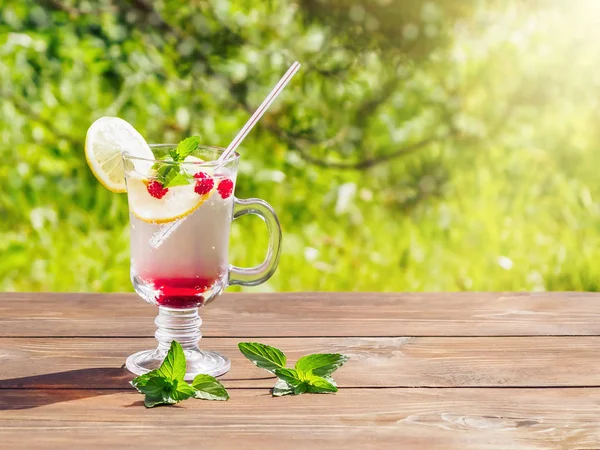 Refrescante cóctel de verano con limón, frambuesa y menta una mesa de madera — Foto de Stock