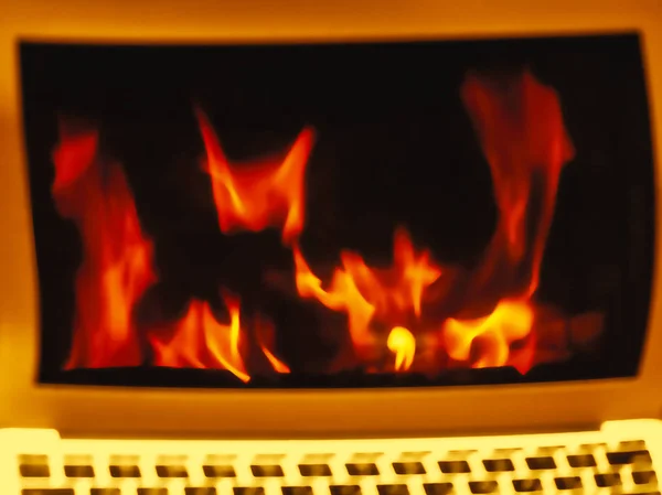 Ноутбук монитор с пламенем на экране, размытый фон — стоковое фото