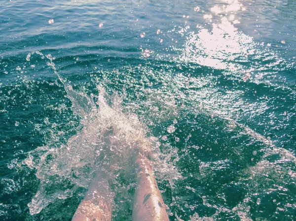 Womens voeten spatten zeewater op een hete zomerdag — Stockfoto
