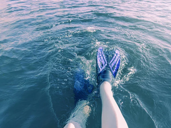 Beine in Schwimmflossen fallen an einem heißen Sommertag in der Sonne ins blaue Wasser — Stockfoto