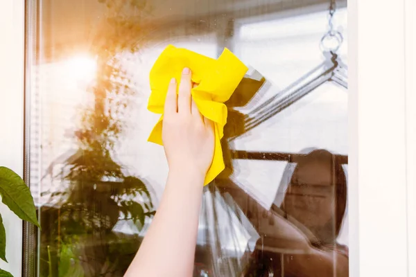 Young woman is reflected in a window that she washes with a rag — Stock Photo, Image