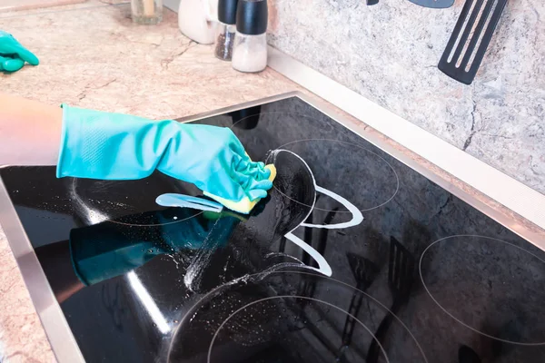 Жінки в рукавичці очищають чорну панель плити — стокове фото