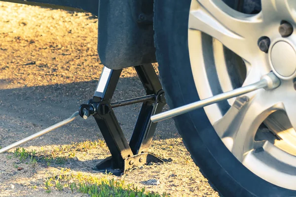 Karayolu üzerindeki tekerlekleri değiştirerek, araba Jacked, bir lastik demir ile fındık vidalanma — Stok fotoğraf