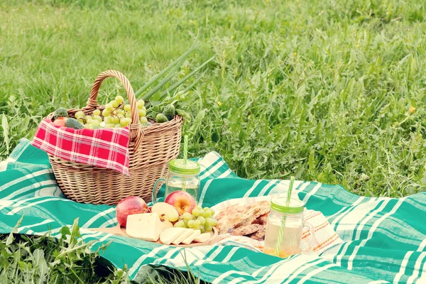 Piknik na trávě v letním dnu-košík, hrozny, sýr, chléb, jablka-koncept letní venkovní rekreace — Stock fotografie